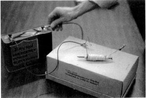 En järnspik magnetiseras med hjälp av ett batteri. Foto.
