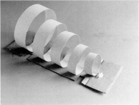Pappersremsor formade till ringar fästa på en bit kartong för att visa hur det reagerar när de skakas. Foto.