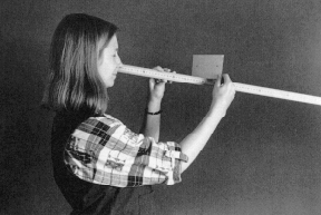 En flicka för en kartongbit med markeringar längs en pinne för att upptäcka den blinda fläcken. Foto.