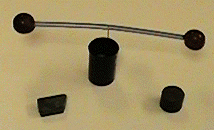 Sugrör med vindruvor i ändarna som balanserar på en nål faststatt i en burk med lock för kamerafilm. Foto