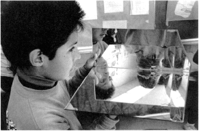 Pojke som håller upp hörnreflektor tillverkad av tre speglar. Foto.