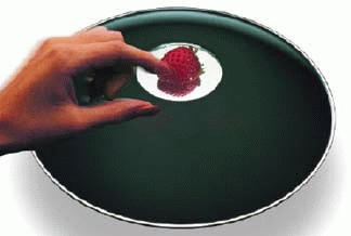 Parabolspegel där den tredimensionella bilden av en jordgubbe svävar i öppningen. Foto.