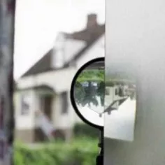 Bild av ett förstoringsglas där man täckt halva linsen med smörpapper för att tydliggöra den upp och nedvända bilden av ett hus i linsen. Foto.