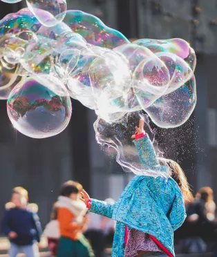 Kvinna som blåser jättesåpbubblor utomhus. Foto.