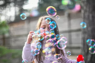 Flicka som blåser såpbubblor. Foto,